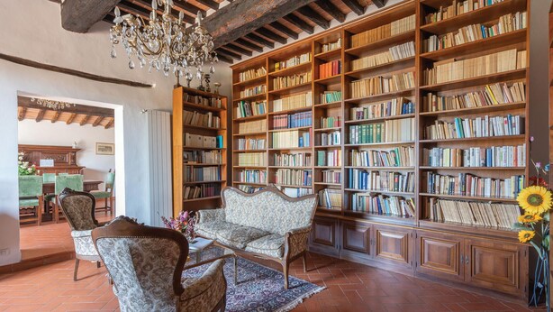 Une bibliothèque avec des étagères, un lustre, des meubles à motifs et un sol carrelé.