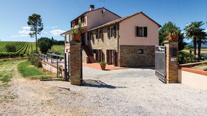 Un bâtiment à deux étages, doté d’une façade en pierre, d’une allée gravillonnée et d’une entrée fermée par un portail.