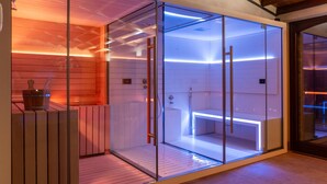 Uma sauna com paredes de vidro, um banco de madeira e outro banco com um balde.