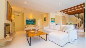 A modern living room with a fireplace, white sofas, a wooden coffee table, and a staircase. - VILLA CALA FIGUERA - Villa with private pool, direct access to the sea and free Wi-Fi (Santanyí)