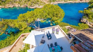 A rooftop terrace with outdoor seating, overlooking a coastal landscape with clear blue waters and rocky terrain. - VILLA CALA FIGUERA - Villa with private pool, direct access to the sea and free Wi-Fi (Santanyí)