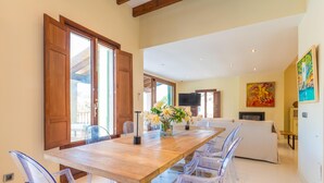 A dining area with a wooden table, clear plastic chairs, and a vase with flowers. - VILLA CALA FIGUERA - Villa with private pool, direct access to the sea and free Wi-Fi (Santanyí)