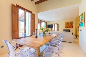 Un comedor con una mesa de madera, sillas de plástico transparente y un jarrón con flores.