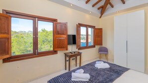 A bedroom with large windows, a bed with towels, a small table, a chair, and a wardrobe. - VILLA CALA FIGUERA - Villa with private pool, direct access to the sea and free Wi-Fi (Santanyí)