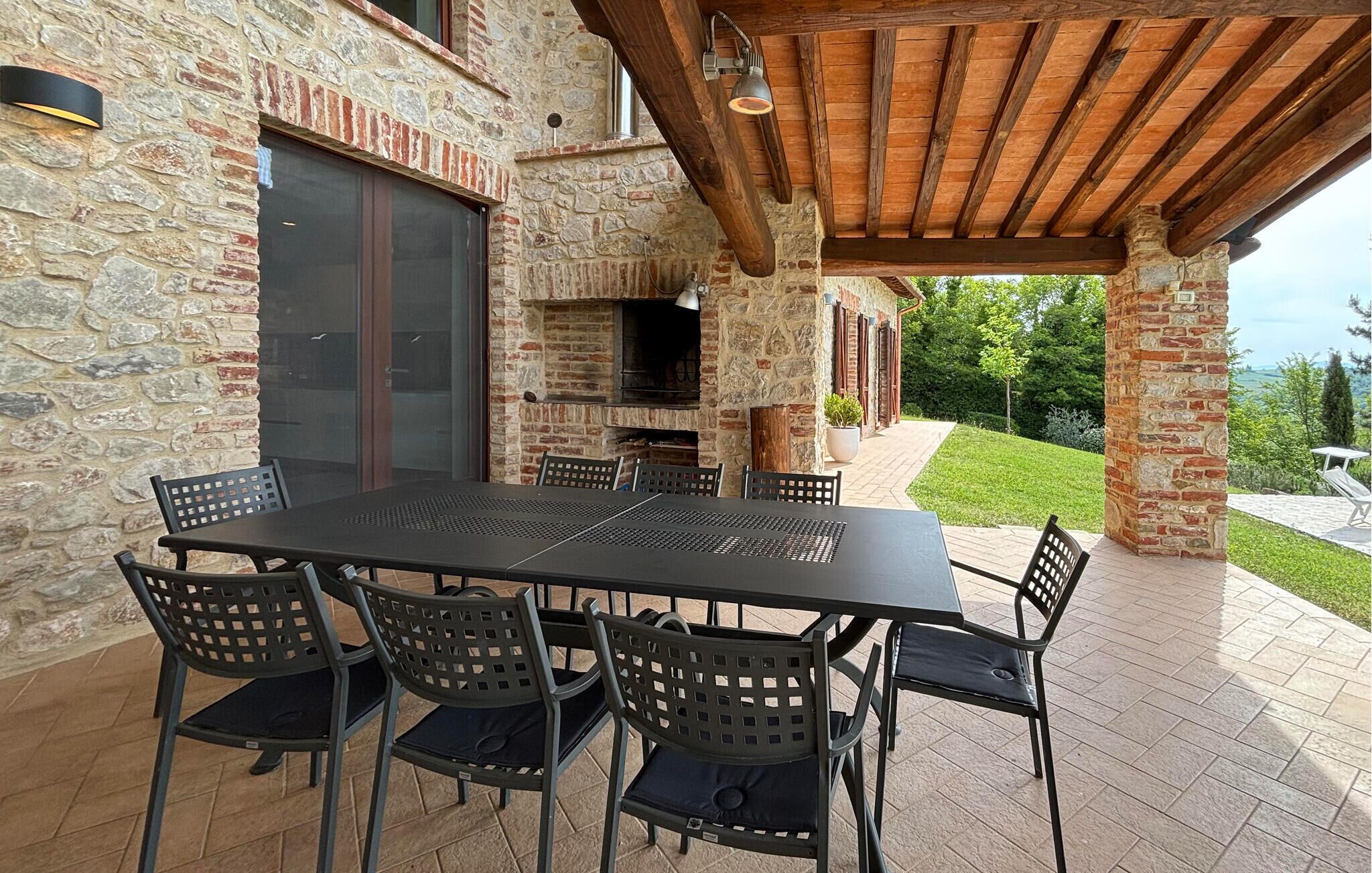 Un patio al aire libre con pared de piedra, chimenea de ladrillo y techo de madera.