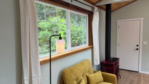 Una habitación con ventana, sofá, lámpara y puerta.