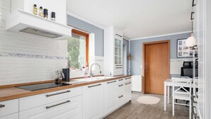 Uma cozinha moderna com armários brancos, bancada de madeira e uma janela.