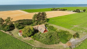 Vista aérea de uma propriedade rural com campos, uma casa e um corpo d'água.