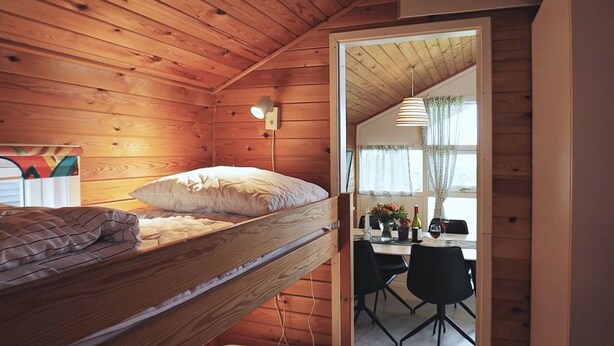 A wooden cabin room with bunk beds, a desk, and a chair.