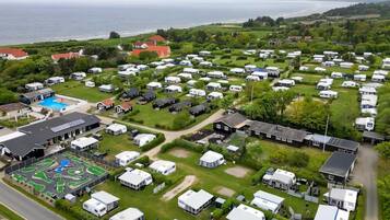 Un terrain de camping équipé d’emplacements pour camping-cars, d’une piscine et de bâtiments dotés de panneaux solaires.