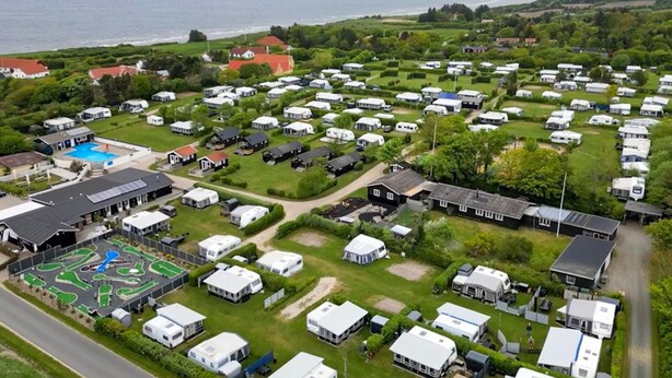 A campground with RVs, a pool, and buildings with solar panels.