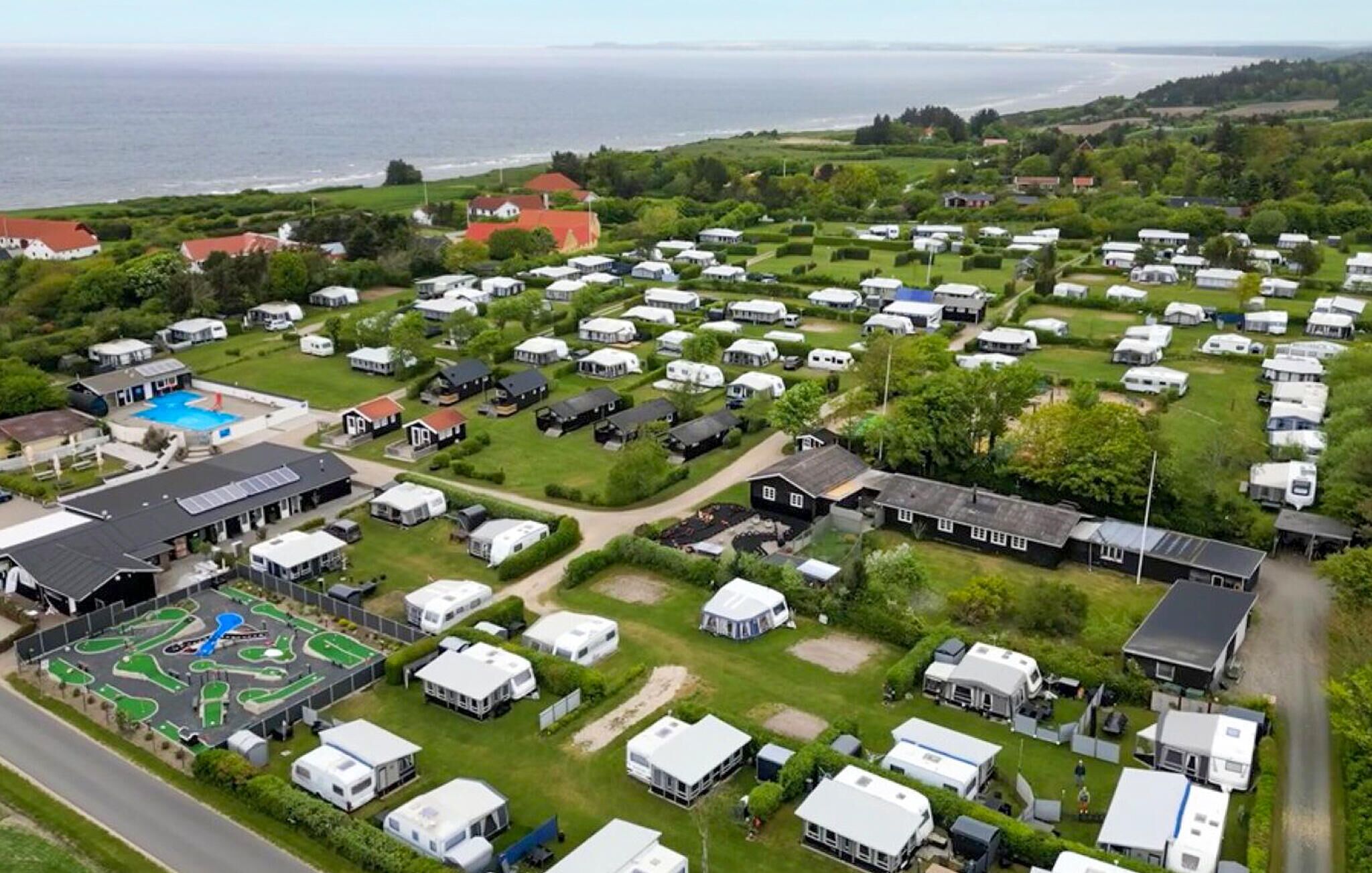 Un terrain de camping équipé d’emplacements pour camping-cars, d’une piscine et de bâtiments dotés de panneaux solaires.