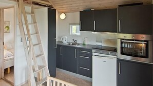 Una cocina compacta con armarios oscuros, un horno empotrado y una escalera apoyada en la pared.