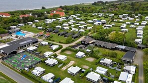 Un grand terrain de camping pour véhicules récréatifs, comprenant de nombreux mobil-homes, une piscine et un parcours de golf.