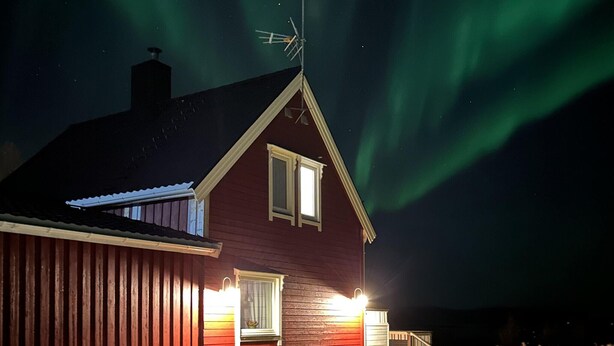 Una casa de fachada roja, con chimenea y antena parabólica.