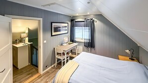 Un dormitorio con cama, escritorio, silla y ventana con cortinas.