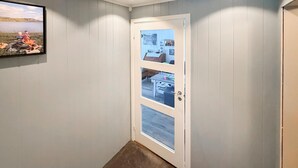Un pasillo con una puerta blanca, un cuadro enmarcado en la pared y piso alfombrado.