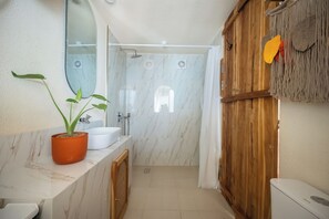 Ein Badezimmer mit Dusche, Waschbecken und Spiegel.
