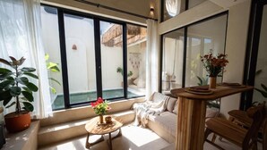 Ein modernes Interieur mit einem großen Fenster, einem Holztisch, einer Couch und einem Blumentopf.
