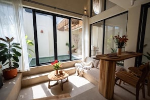 Ein modernes Interieur mit einem großen Fenster, einem Holztisch, einer Couch und einem Blumentopf.
