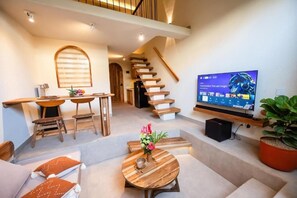Ein modernes Wohnzimmer mit Treppe, einem Fernseher, der 'Transformers: The Last Knight' zeigt, und einer Zimmerpflanze.