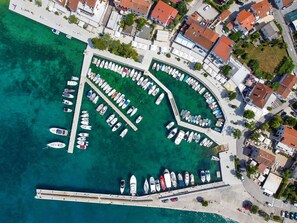 Eine Vogelperspektive auf einen Yachthafen mit zahlreichen dort vertäuten Booten, umgeben von Wohngebäuden und einer klaren Uferlinie.