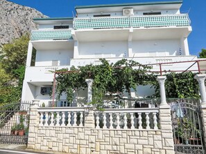 A multi-story building with a white facade, green-tiled balconies, and a stone wall with a wrought iron gate. - Gemütliche Ferienwohnung in Strandnähe by Interhome (Drašnice)