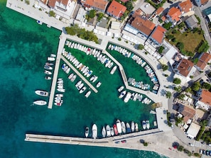 An aerial view of a marina with numerous boats docked, surrounded by residential buildings and a clear waterfront. - Apartment Mladen - 2 by Interhome (Krk/Njivice)
