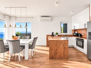 A modern kitchen with a wooden island, white cabinetry, and a view of the sea. - Villa Vip in Makarska mit beheiztem Pool und 4 Schafzimmern by Interhome (Makarska)