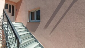 A staircase leading to a door with a window, a metal railing, and a textured wall. - Apartment Raspolic no.2 by Interhome (Opatija/Kastav)