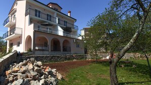 A multi-story building with balconies, a stone wall, and a grassy area with a tree. - Apartment Raspolic no.2 by Interhome (Opatija/Kastav)