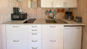 Een kleine keuken met een magnetron, spoelbak en kasten.
