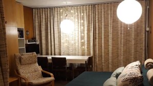 Een kamer met een bed, een bureau, een stoel en gordijnen.