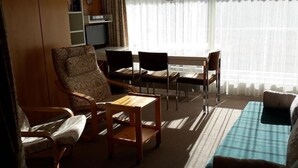 Een woonkamer met een bank, stoelen, een klein tafeltje en een televisie.