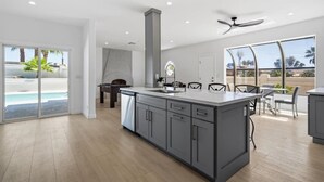 Una cocina moderna con una isla grande, un comedor y vistas a una piscina.