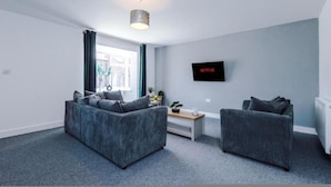 Ein modernes Wohnzimmer mit zwei Sofas, einem Couchtisch und einem an der Wand befestigten Fernseher.