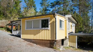 A small, yellow cabin with a porch, surrounded by trees. - Nice home in Brottby with house a panoramic view (Brottby)