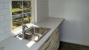 A kitchen with a stainless steel sink, white tiled backsplash, and a window overlooking a garden. - Nice home in Brottby with house a panoramic view (Brottby)