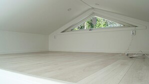 Een kamer met een schuine kap, dakraam en houten vloer.