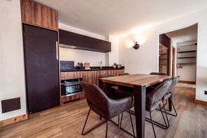 Eine moderne Küche mit einem Holzespeisetisch und -stühlen, einem eingebauten Backofen und einem Kühlschrank.