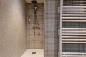 Ein modernes Badezimmer mit Dusche, Handtuchhalter und einer Wand mit Struktur.
