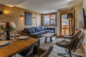 Ein modernes Interieur mit einer Holzwand, einer Couch, einem Esstisch und Ledersesseln.