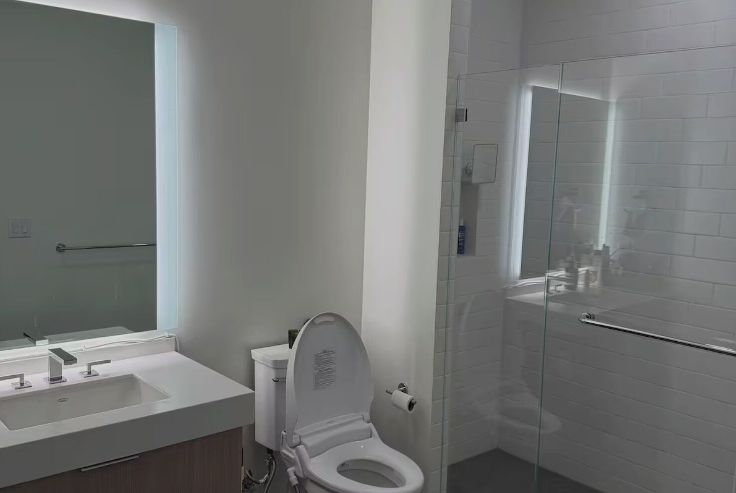 A modern bathroom with a toilet, sink, and glass shower enclosure.