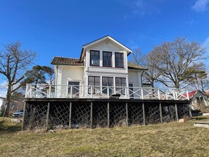 A two-story house with a balcony and a fenced deck. - 5 Star Holiday Home in Dalaro (Dalaro)