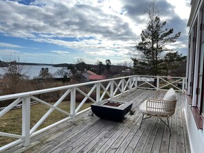 A wooden deck with a white railing, a black fire pit, and a wicker chair. - 5 Star Holiday Home in Dalaro (Dalaro)