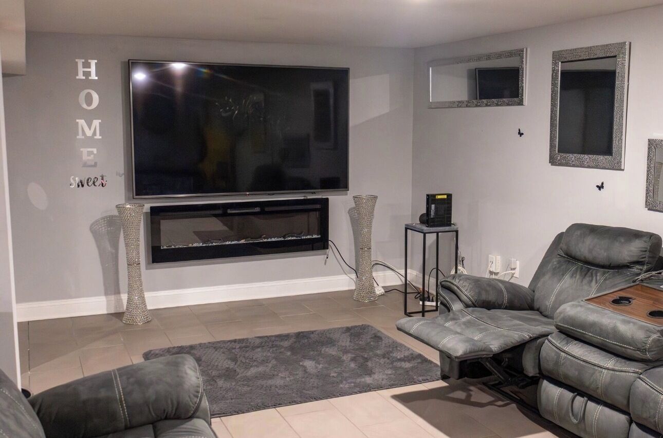 A living room with a flat-screen TV, a fireplace, a leather sofa, and a coffee table.