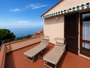 Ein Balkon mit zwei Loungestühlen, einer Champagnerflasche und Meerblick.