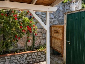 Eine Steinmauer, eine Holztür mit der Aufschrift 'DOCCIA ESTERNA' und ein grünes Tor.
