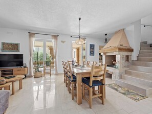 A spacious living area with a dining table, chairs, a flat-screen TV, and a fireplace. - Villa Javor by Interhome (Pula/Krnica)