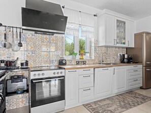 A kitchen with white cabinets, a stove, oven, and a refrigerator. - Villa Javor by Interhome (Pula/Krnica)